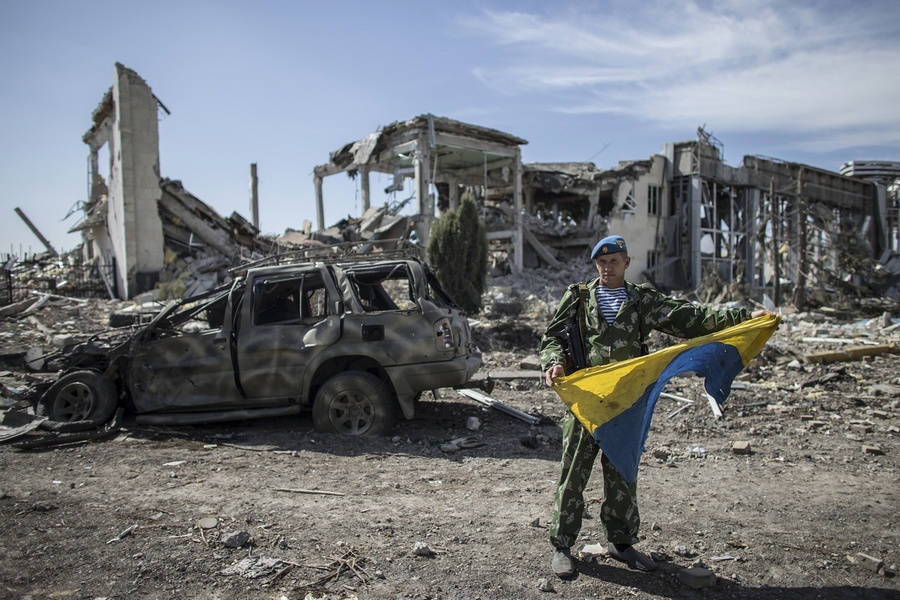 Yakut, an ex-Russian paratrooper, displays a captured Ukrainian flag at the destroyed airport in Luhansk